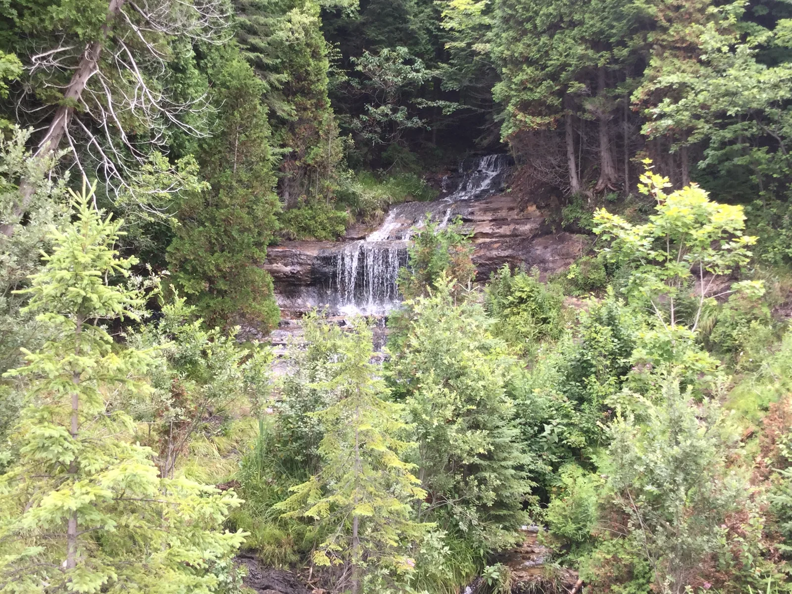 Alger Falls flowing over a roadside cliff in Munising, easily visible from the highway.