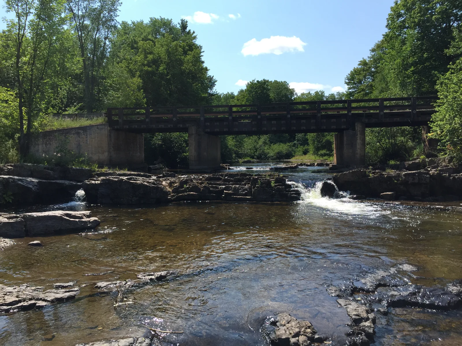 Wooden bridge crossing the Huron River over rocky cascades at Big Eric's Bridge State Forest Campground.