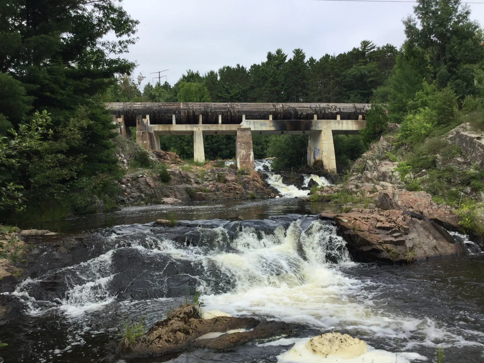 Wright Street Falls — the lower Dead River spilling over rock ledges below the pipeline aqueduct bridge in Marquette.