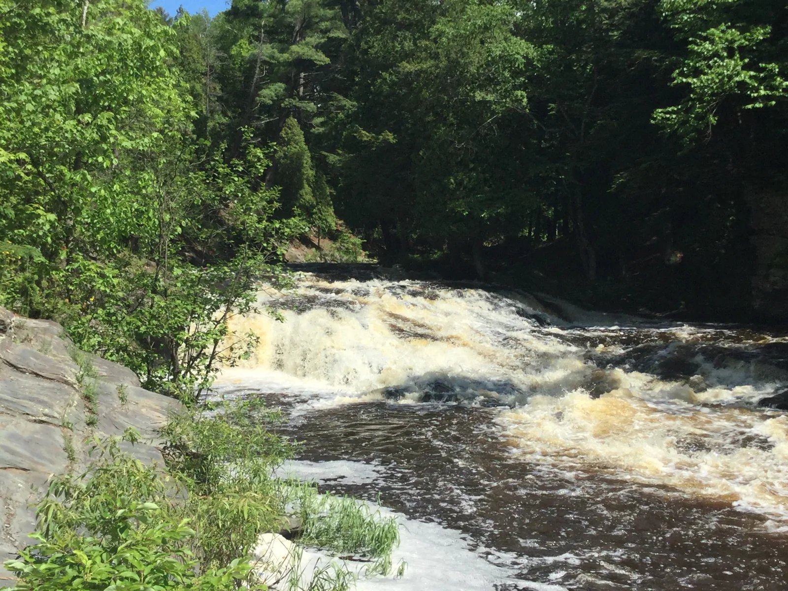 A tannin-stained ledge drop on the Falls River in L'Anse running high after rain.
