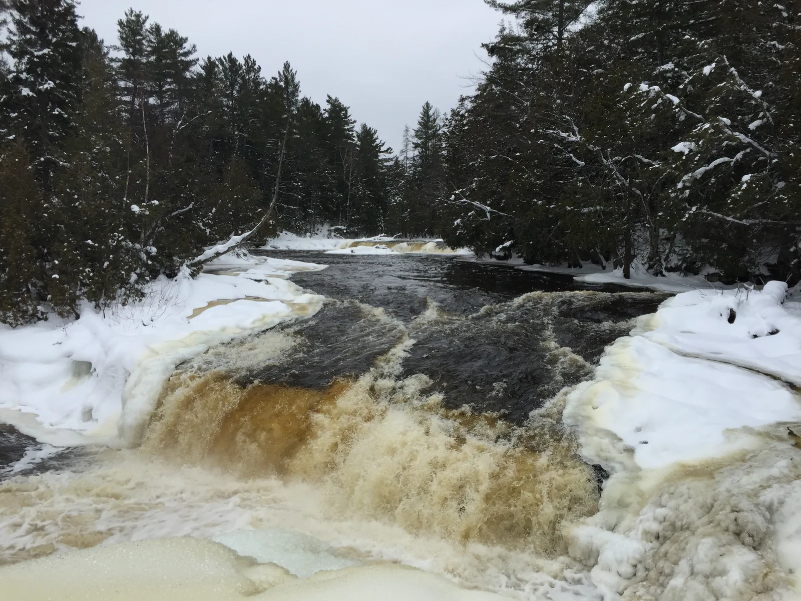 Lower Tahquamenon Falls in winter — one of the smaller drops around the island, with snow lining the banks.
