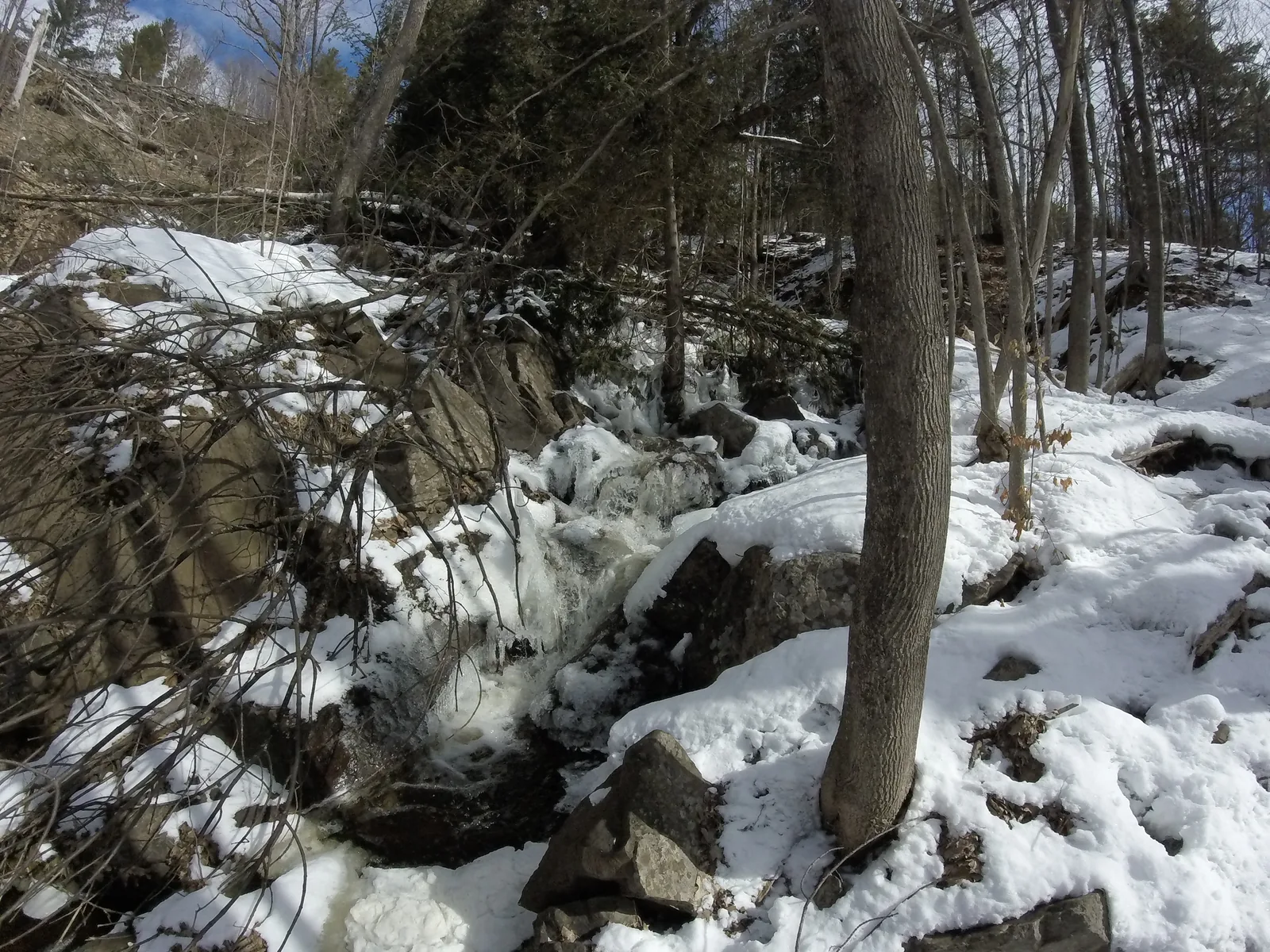 Ripley Falls in winter — partially frozen cascade flowing over rocks on the steep slope of Mont Ripley.