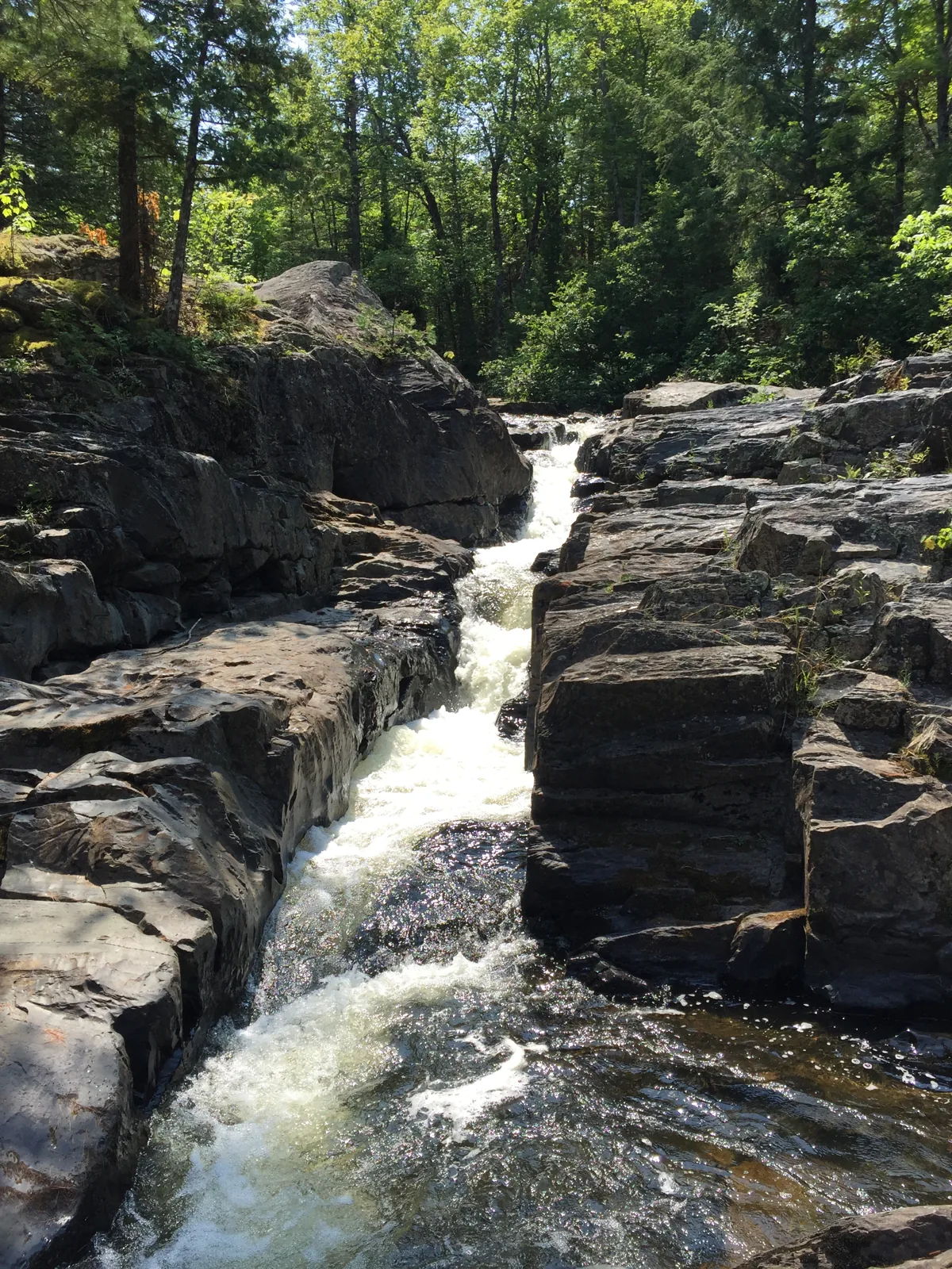 Silver Falls channeled through a narrow slot in blocky black rock on the Silver River near L'Anse.