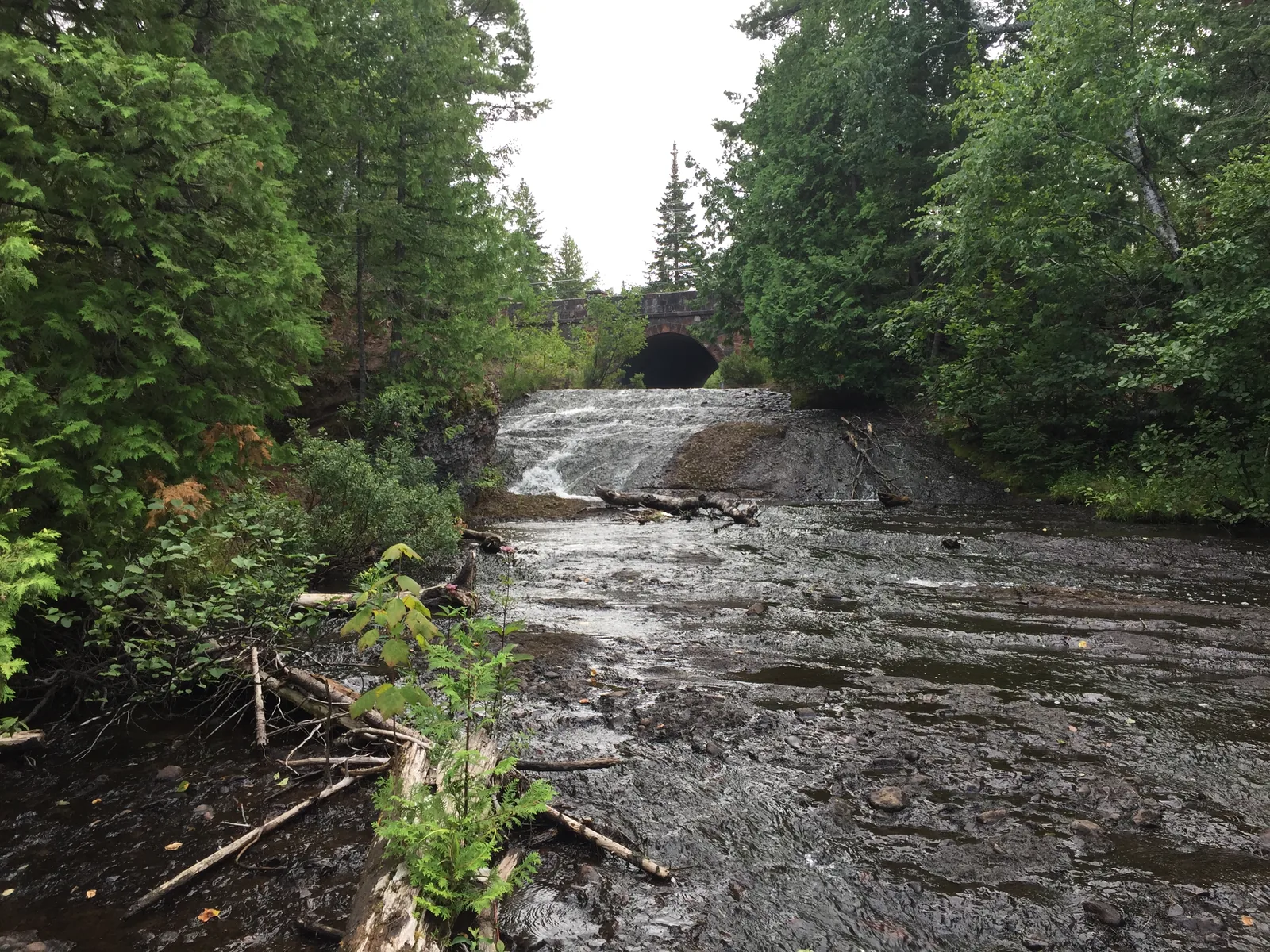 Silver River Falls — a wide flowing slide of water under a historic stone arch bridge in Keweenaw County.