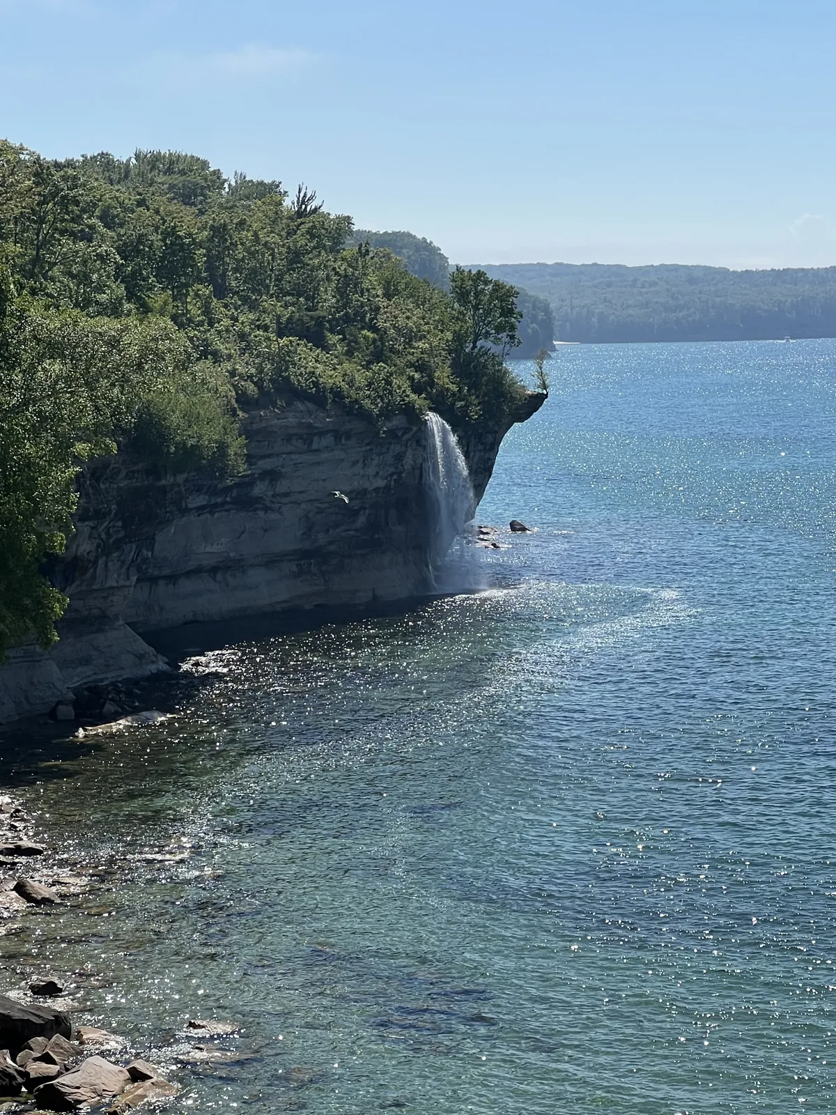 Spray Falls plunging 70 feet off the Pictured Rocks cliffs straight into Lake Superior on a clear summer day.