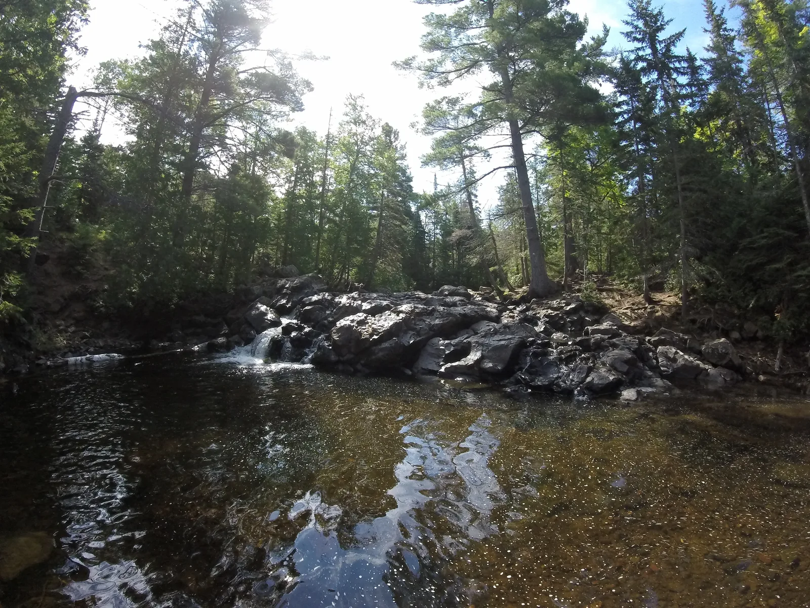 Ten Foot Falls running with spring snowmelt over rocky ledges, with snow still piled along the banks.